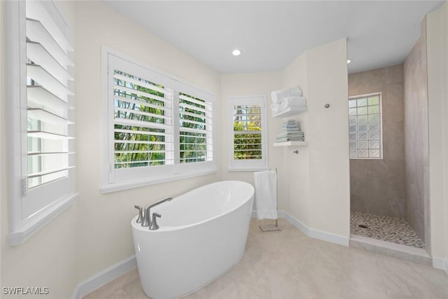 full bath featuring tile patterned floors, a freestanding tub, recessed lighting, baseboards, and walk in shower