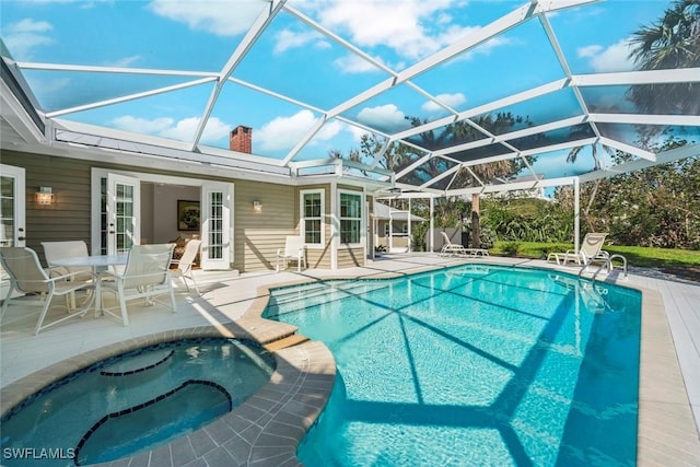 view of pool with a patio area, french doors, a pool with connected hot tub, and a lanai