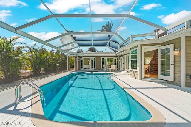 pool featuring glass enclosure, a patio, and a wooden deck