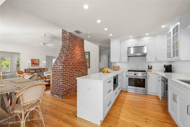 kitchen featuring visible vents, under cabinet range hood, a peninsula, built in microwave, and high end range