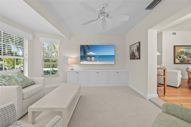 living area featuring a ceiling fan, baseboards, visible vents, and light carpet