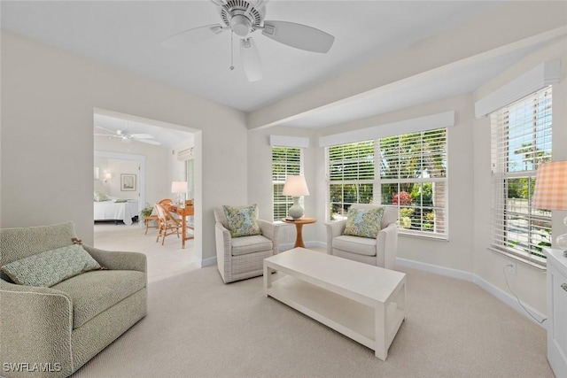 sitting room with baseboards, light carpet, and a ceiling fan