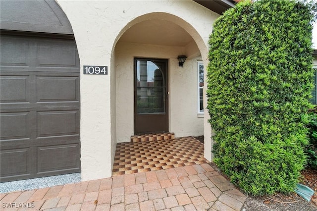 doorway to property featuring a garage and stucco siding