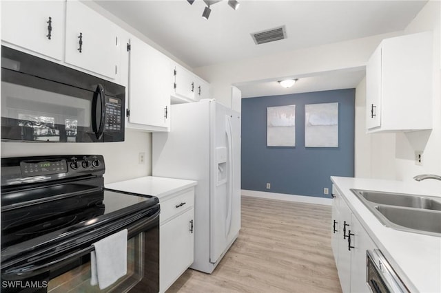 kitchen featuring visible vents, light wood-style floors, light countertops, black appliances, and a sink