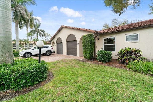 view of side of home featuring an attached garage, a tile roof, a lawn, and stucco siding