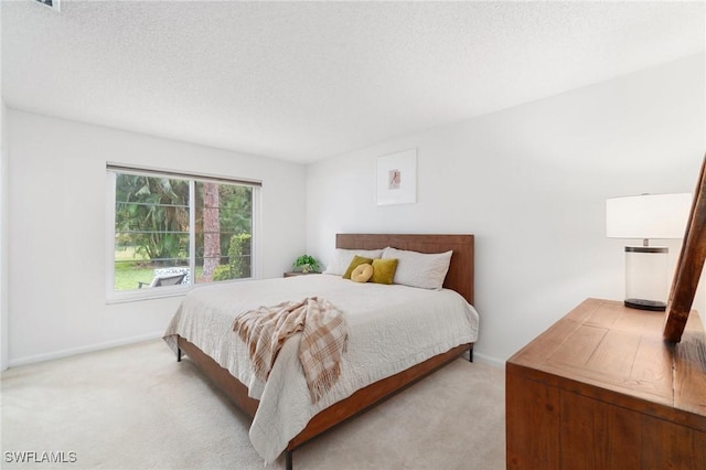 bedroom featuring light carpet, a textured ceiling, and baseboards