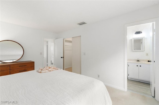 bedroom with light colored carpet, visible vents, connected bathroom, a sink, and baseboards