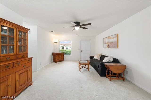 living area with light carpet, ceiling fan, and baseboards