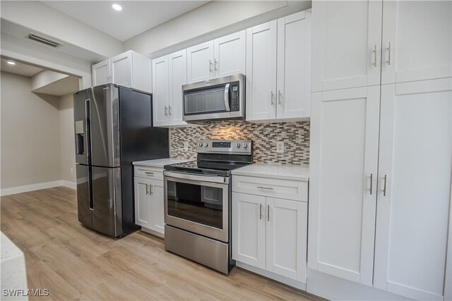 kitchen with visible vents, light countertops, appliances with stainless steel finishes, decorative backsplash, and light wood finished floors