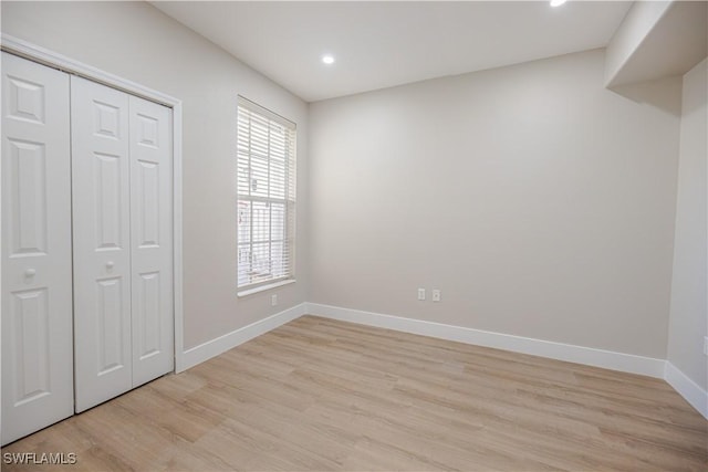 unfurnished bedroom with recessed lighting, a closet, light wood finished floors, and baseboards