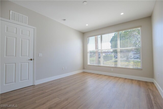 empty room featuring light wood-style floors, baseboards, visible vents, and recessed lighting