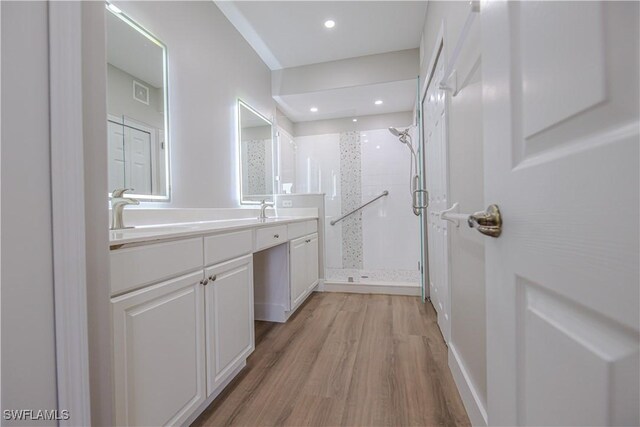 bathroom featuring wood finished floors, a sink, a shower stall, and double vanity