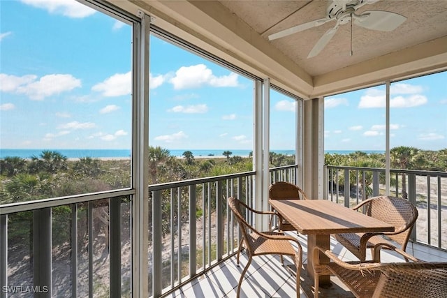 sunroom / solarium with a water view, plenty of natural light, and a ceiling fan