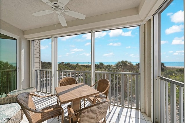 sunroom / solarium with a water view and a ceiling fan