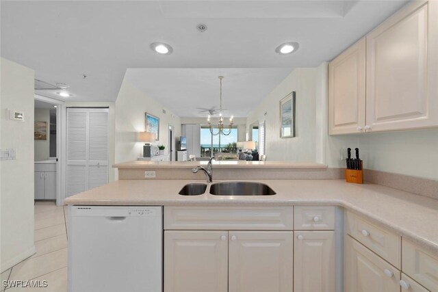 kitchen featuring a peninsula, white dishwasher, light countertops, and a sink