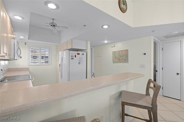 kitchen featuring light tile patterned floors, white refrigerator with ice dispenser, stainless steel microwave, a peninsula, and recessed lighting