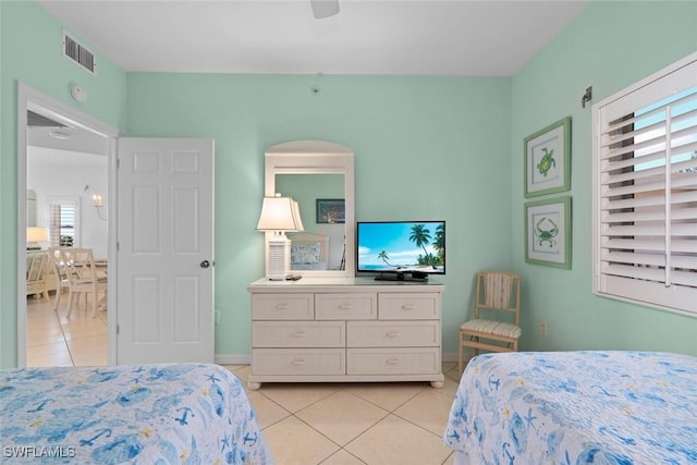 bedroom featuring a ceiling fan, visible vents, baseboards, and light tile patterned floors