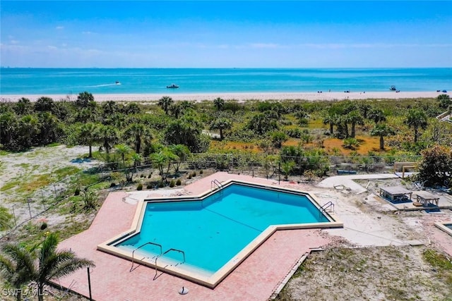 pool with a patio, a water view, and fence