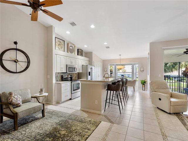 kitchen featuring baseboards, visible vents, stainless steel appliances, and open floor plan