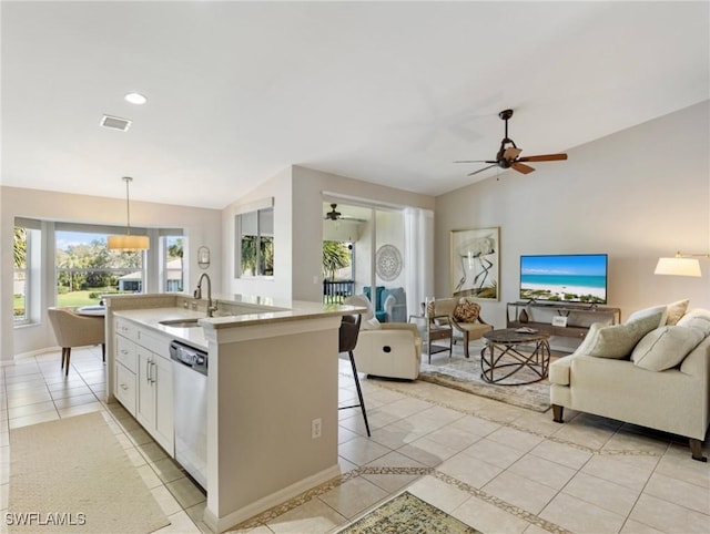 kitchen featuring light tile patterned floors, stainless steel dishwasher, open floor plan, vaulted ceiling, and a sink