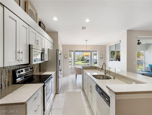 kitchen with a large island, light tile patterned floors, tasteful backsplash, appliances with stainless steel finishes, and a sink