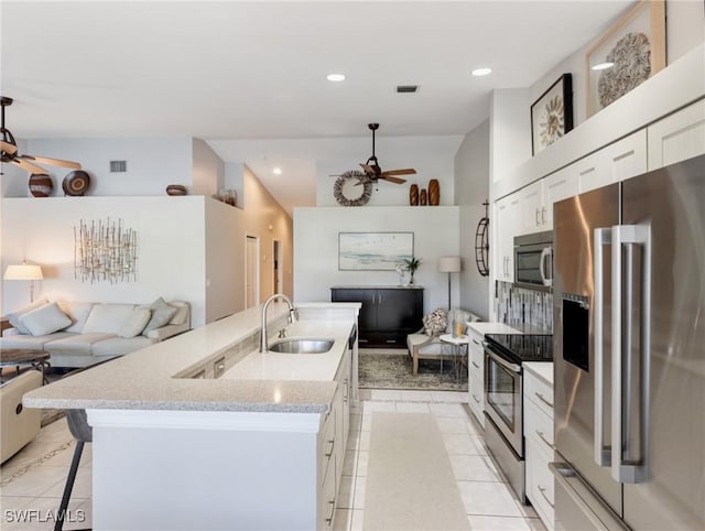 kitchen featuring light tile patterned floors, stainless steel appliances, a ceiling fan, open floor plan, and a sink