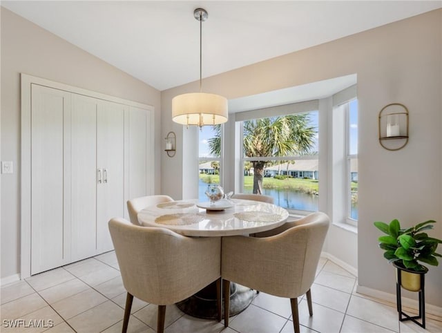 dining space with a water view, light tile patterned floors, baseboards, and vaulted ceiling