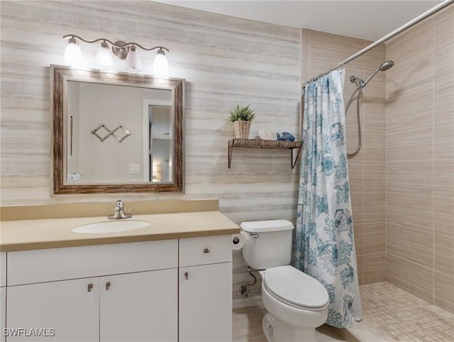 bathroom featuring toilet, a tile shower, and vanity