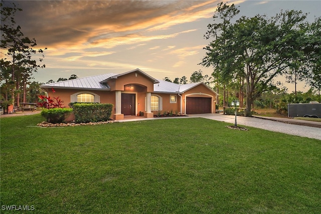 ranch-style house with a garage, a front yard, metal roof, and driveway