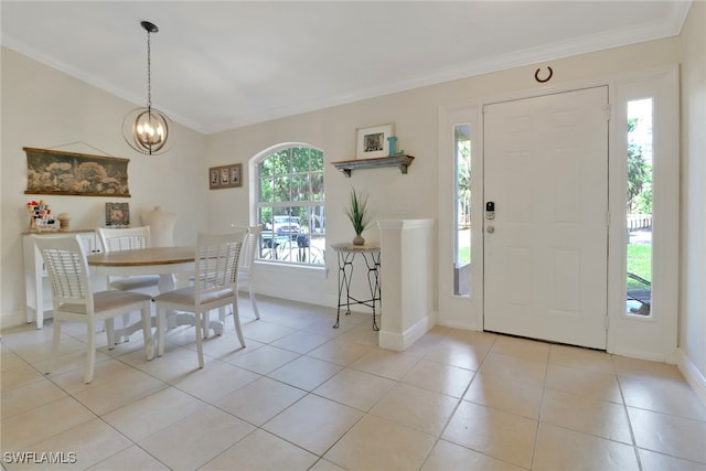 foyer entrance with light tile patterned floors, ornamental molding, and a notable chandelier