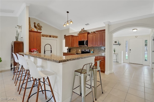 kitchen featuring a breakfast bar, light tile patterned floors, stainless steel appliances, and backsplash