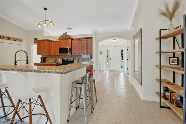 kitchen featuring tasteful backsplash, a kitchen breakfast bar, stainless steel appliances, a sink, and light tile patterned flooring