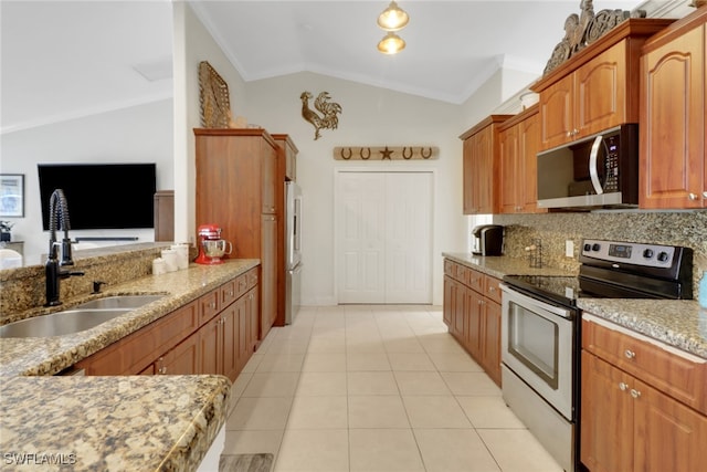 kitchen with light tile patterned floors, light stone counters, vaulted ceiling, stainless steel appliances, and a sink