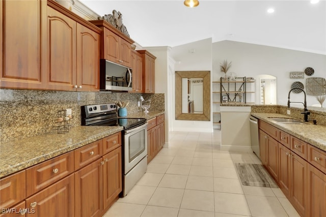 kitchen with light tile patterned floors, a sink, vaulted ceiling, appliances with stainless steel finishes, and decorative backsplash