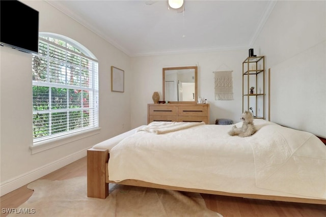 bedroom featuring ornamental molding, light wood-style floors, and baseboards