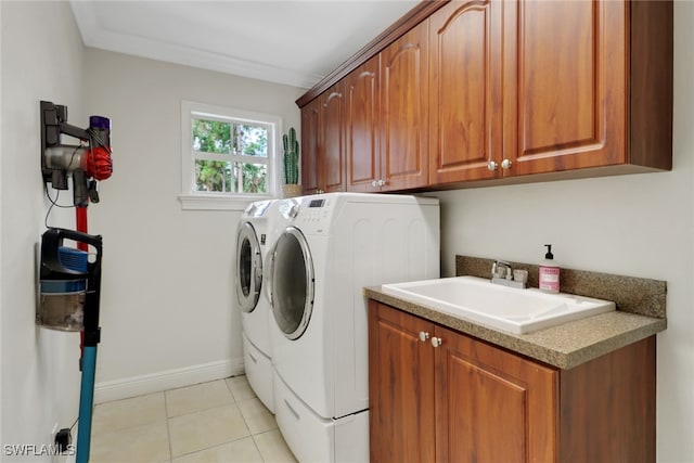 laundry room featuring light tile patterned floors, cabinet space, washing machine and dryer, a sink, and baseboards