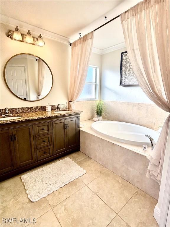 full bath with double vanity, a garden tub, ornamental molding, and a sink