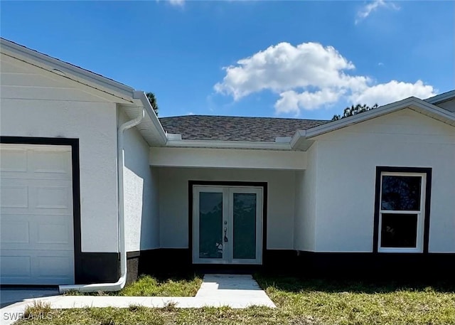 doorway to property featuring a garage, french doors, a shingled roof, and stucco siding