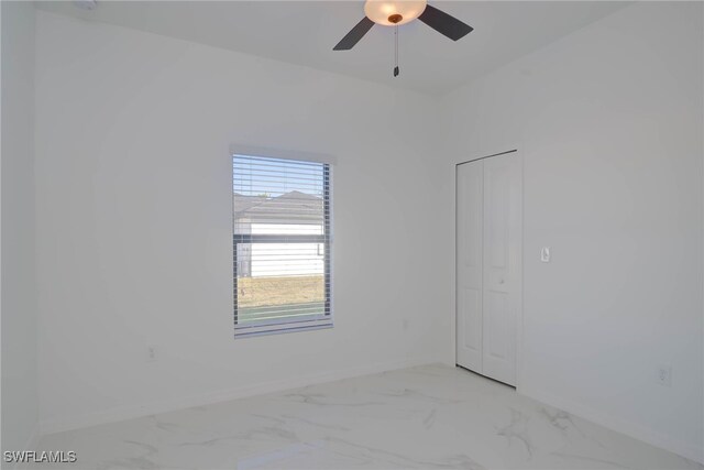 unfurnished room with marble finish floor, a ceiling fan, and baseboards