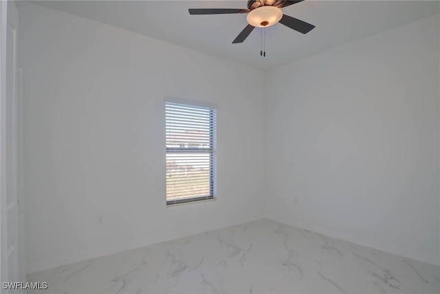 spare room featuring a ceiling fan, marble finish floor, and baseboards