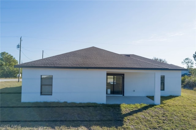 back of property featuring a shingled roof and a lawn