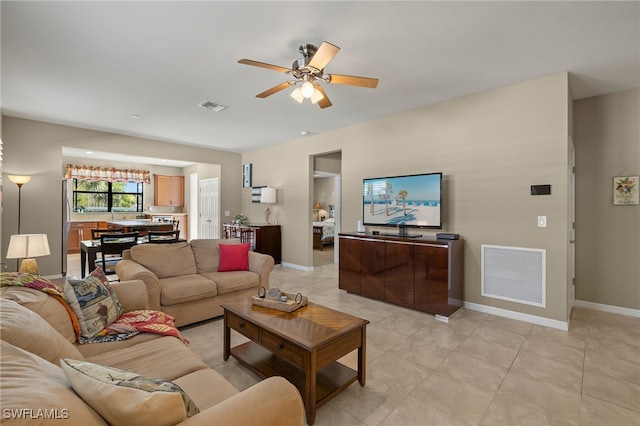 living area with light tile patterned floors, a ceiling fan, visible vents, and baseboards