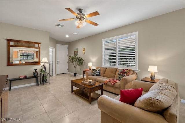 living room featuring light tile patterned floors, ceiling fan, visible vents, and baseboards