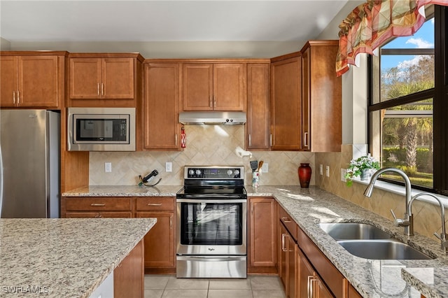 kitchen with light tile patterned floors, decorative backsplash, appliances with stainless steel finishes, a sink, and under cabinet range hood