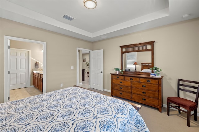 bedroom featuring light carpet, visible vents, baseboards, connected bathroom, and a tray ceiling