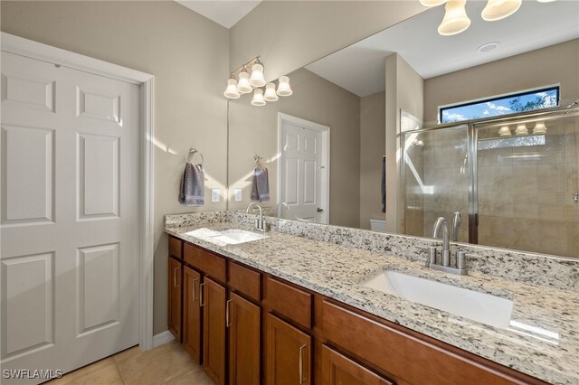 full bath featuring double vanity, a stall shower, toilet, and a sink