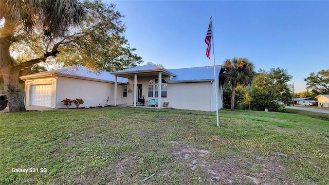 view of front of house with a garage, metal roof, a front lawn, and stucco siding