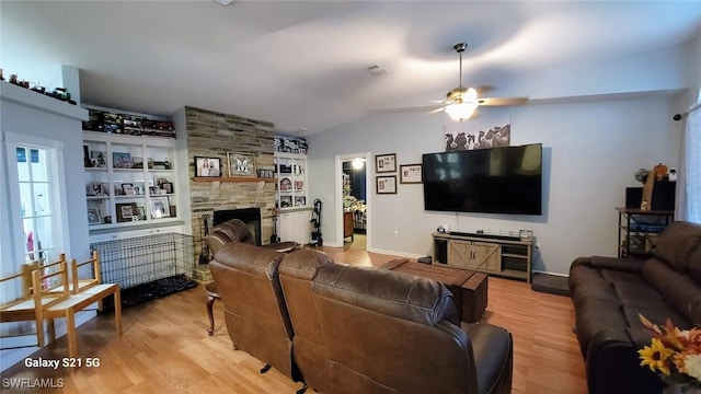 living area featuring built in features, a fireplace, lofted ceiling, ceiling fan, and wood finished floors