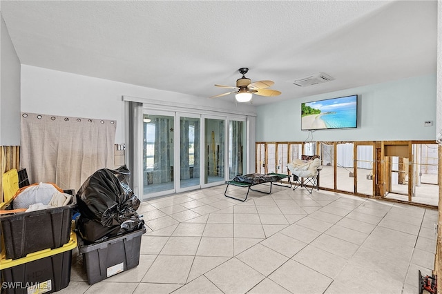 interior space with tile patterned flooring, visible vents, ceiling fan, and a textured ceiling