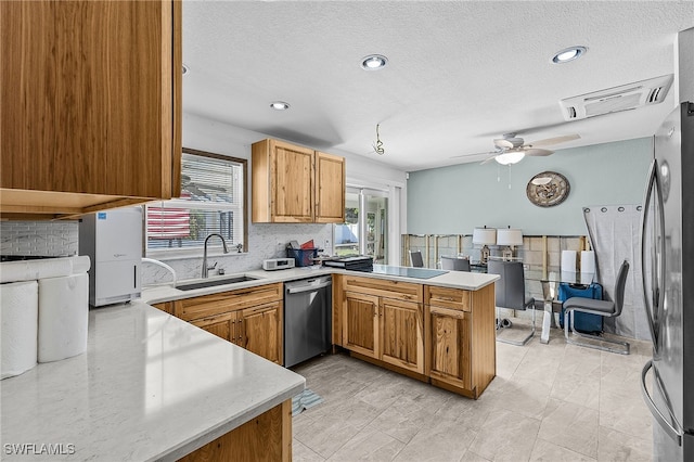 kitchen with visible vents, a peninsula, stainless steel appliances, light countertops, and a sink